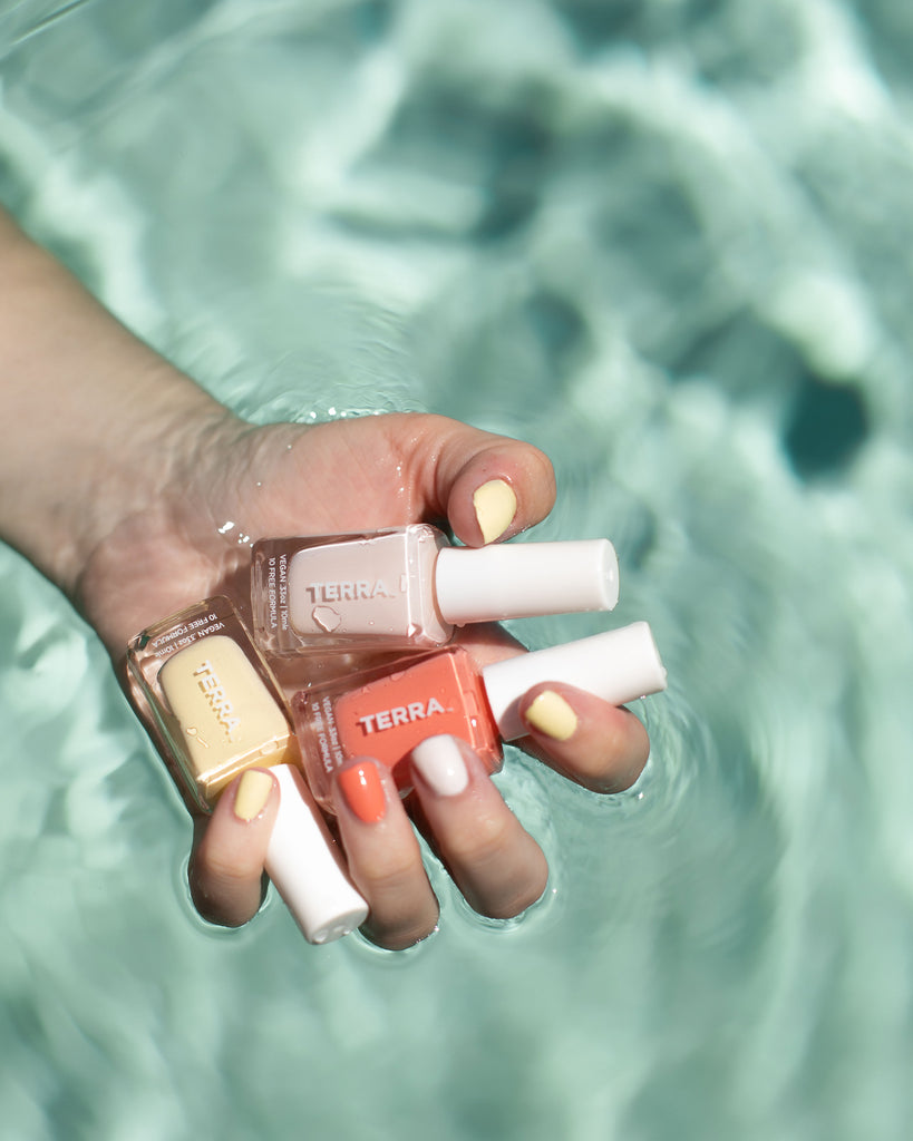 Terra Beauty Bars Summer Trio Refreshments Collection Nail Polish in glass packaging and white caps to include number 34 Sweet Lemonade (light yellow), number 35 White Frosty Pink (soft white pink), number 36 Watermelon Coral color held in a pool and swatched on nails