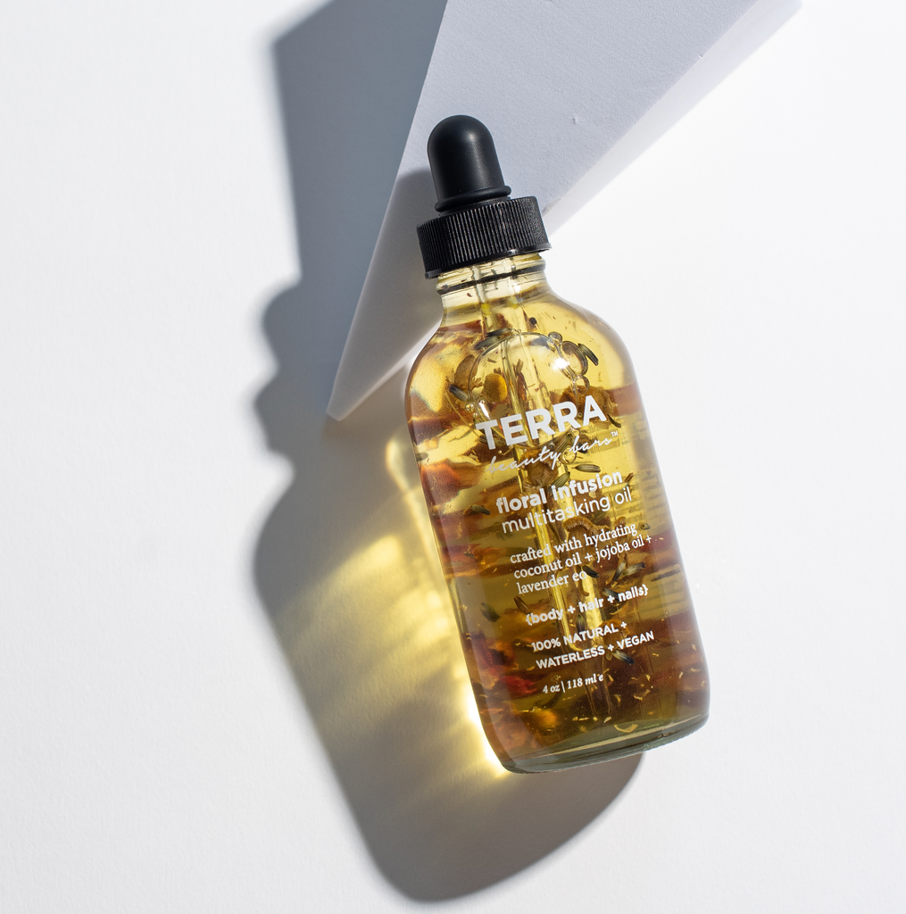 Terra Beauty Floral Infusion Multitasking oil made with jojoba and coconut oil and botanicals floating inside of rose, chamomile and lavender in 4 oz glass bottle with dropper