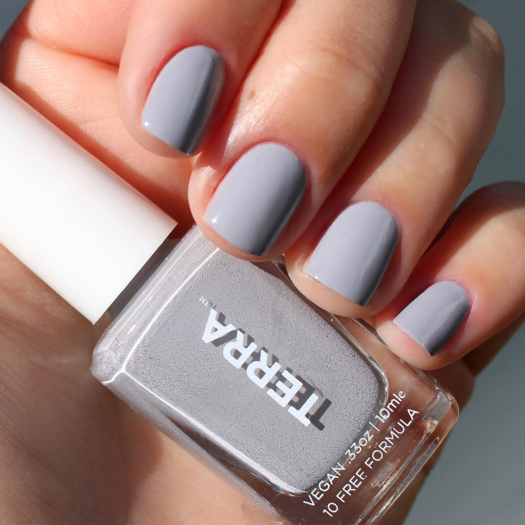 No. 3 Gray (a Terra Founder Fav, this color works all year long and sits between a true light cement to cooler blue-gray shade) swatched on nails and holding terra bottle