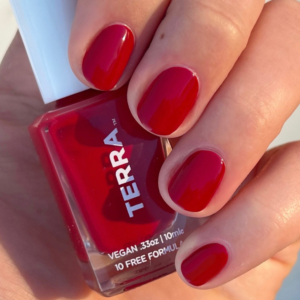 No. 46 Crimson (a captivating red wine hue) swatched on nails and holding terra bottle.