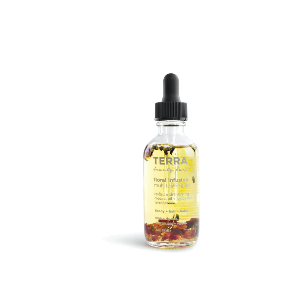 Terra Beauty Floral Infusion Multitasking oil made with jojoba and coconut oil and botanicals floating inside of rose, chamomile and lavender in 2 ounce glass bottle with dropper