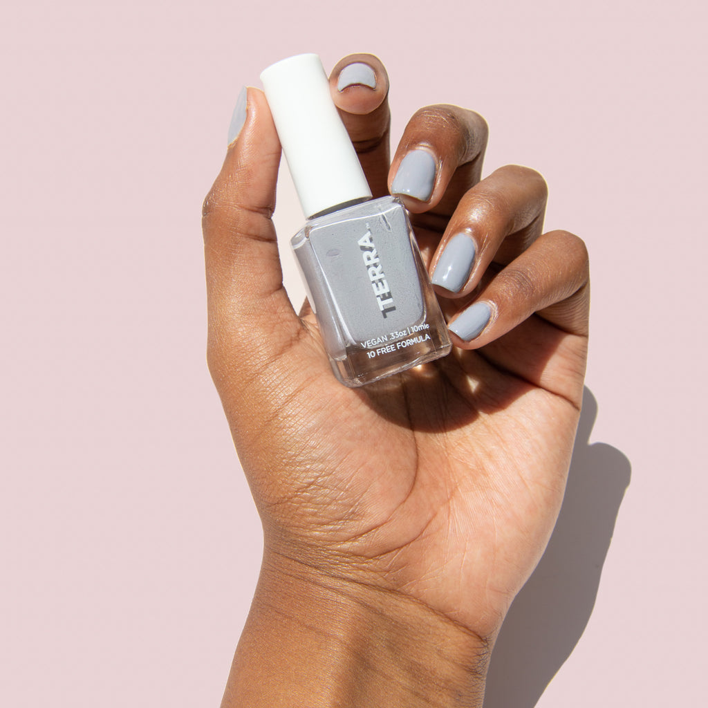 No. 3 Gray (a Terra Founder Fav, this color works all year long and sits between a true light cement to cooler blue-gray shade) swatched on nails and holding terra bottle.